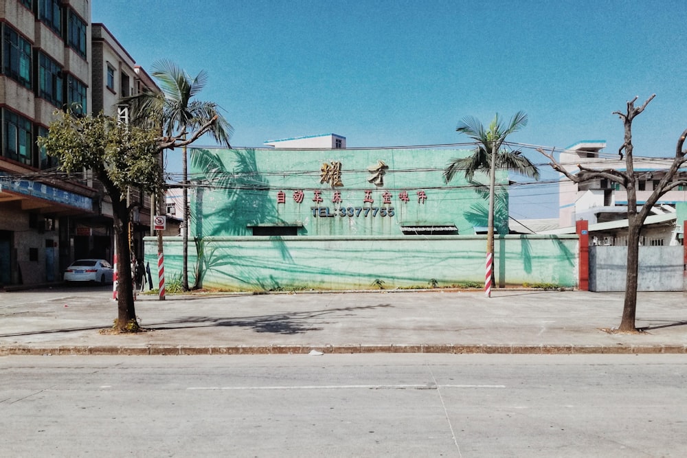 bâtiment en béton vert et blanc près d’un palmier vert sous un ciel bleu pendant la journée