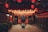A richly decorated interior space is filled with rows of hanging red lanterns casting a warm glow. Stone statues of mythological creatures guard a central altar, surrounded by intricate carvings and traditional architecture. The atmosphere is serene and reverent.