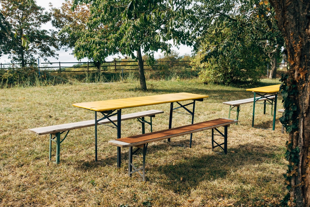 brown wooden picnic table on green grass field during daytime