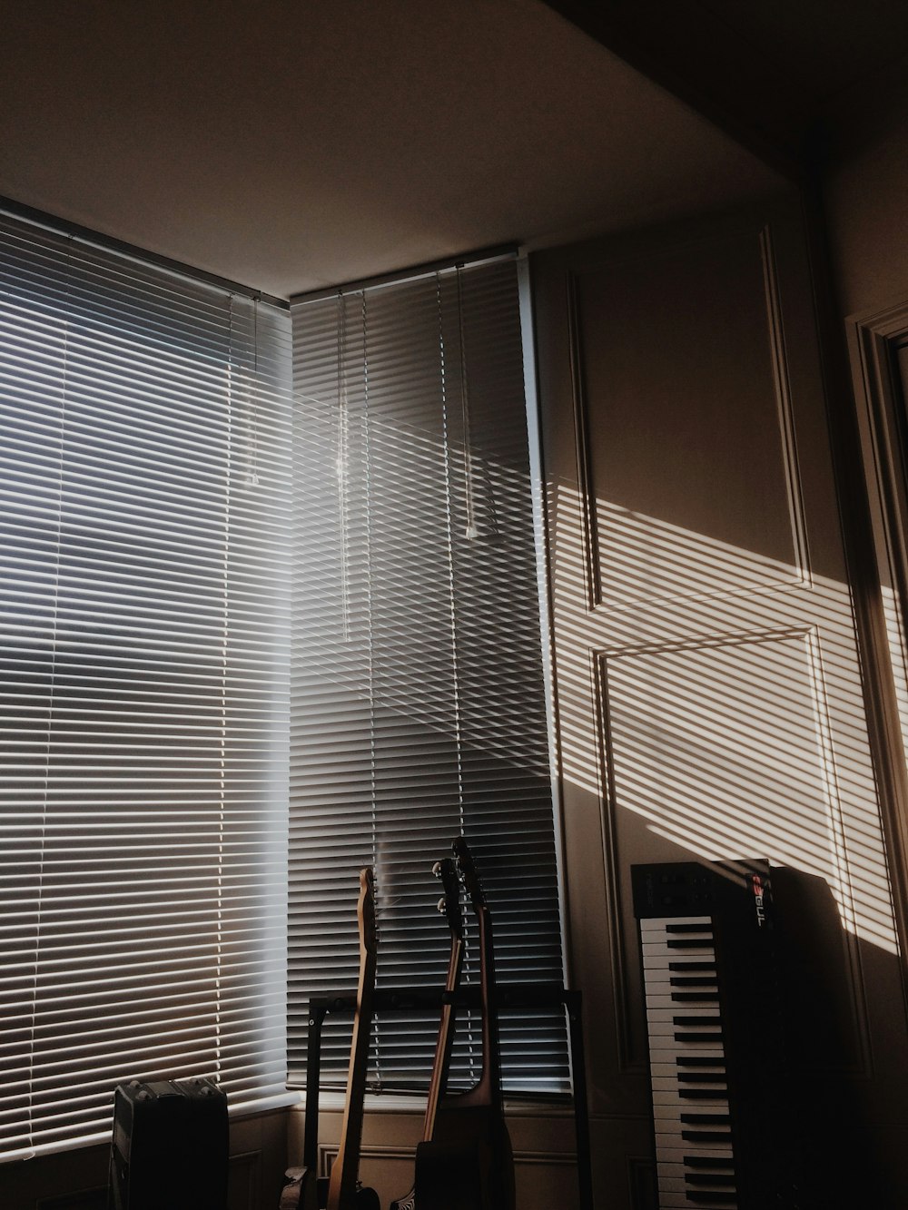 white window blinds near black electric piano