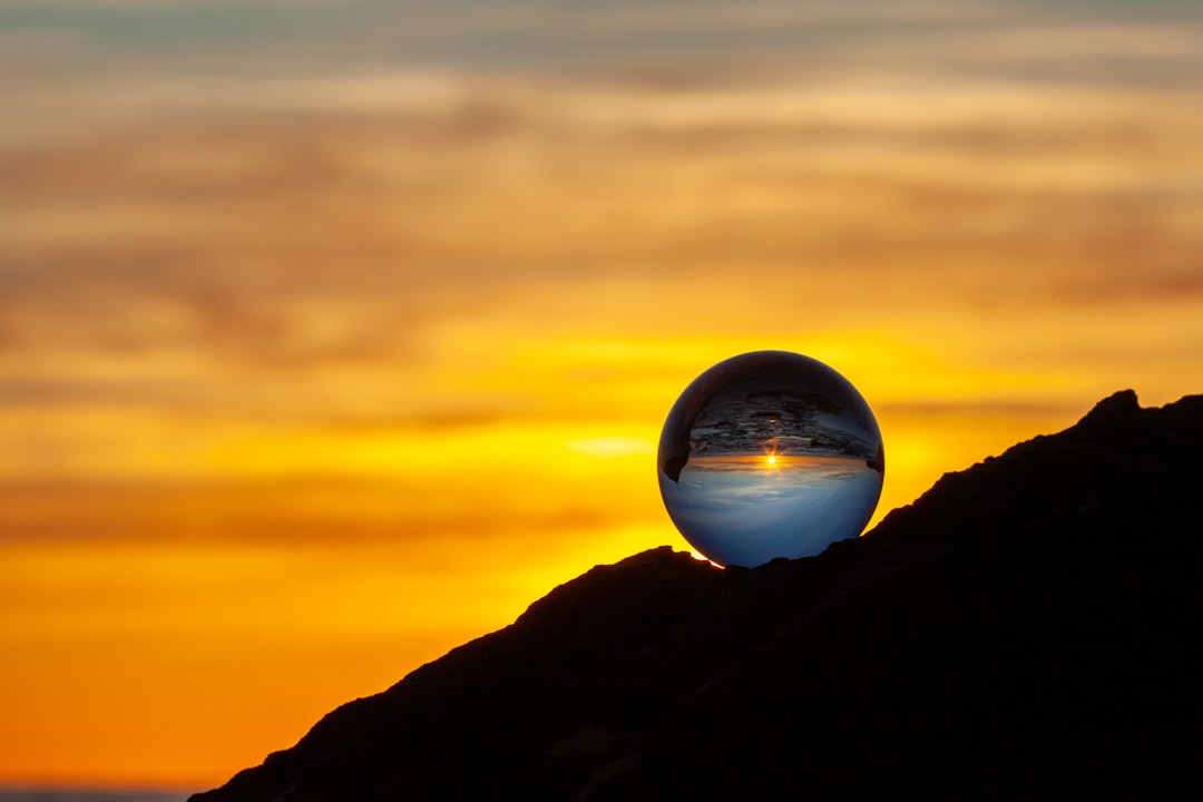 clear glass ball on black mountain during sunset