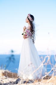 woman in white wedding dress standing on brown grass field during daytime