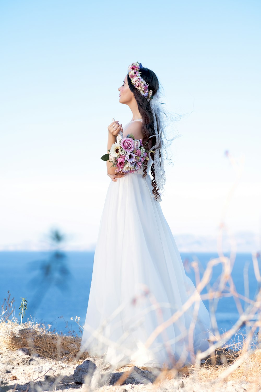 woman in white wedding dress standing on brown grass field during daytime