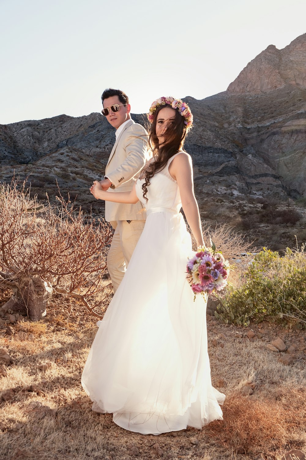 hombre y mujer en vestido de novia de pie en el campo de hierba marrón durante el día