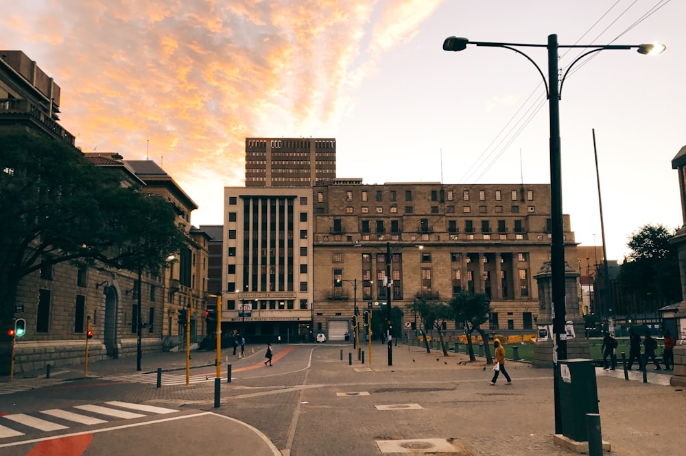 persone che camminano sul marciapiede vicino a un edificio in cemento marrone durante il giorno