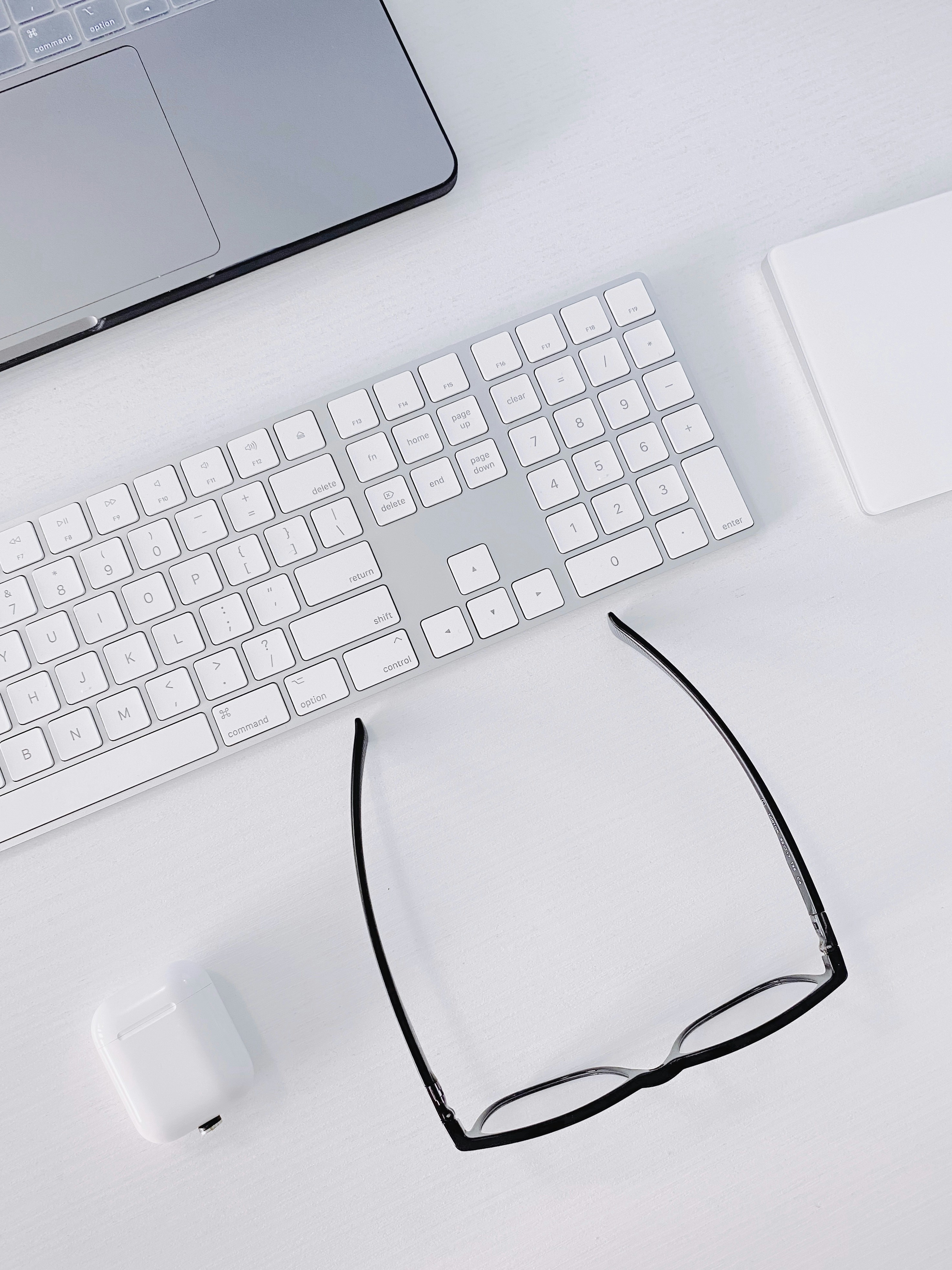 un teclado, mouse y gafas de computadora en un escritorio