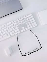 a computer keyboard, mouse, and glasses on a desk
