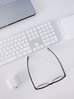 a computer keyboard, mouse, and glasses on a desk