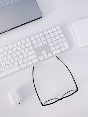 a computer keyboard, mouse, and glasses on a desk