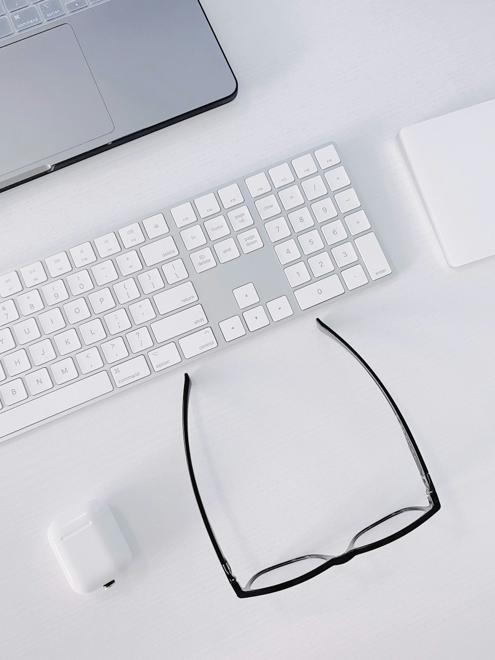 a computer keyboard, mouse, and glasses on a desk