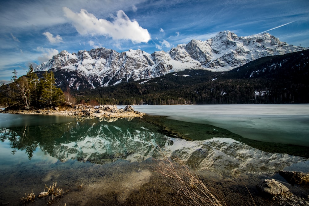 lago perto da montanha coberta de neve sob o céu azul durante o dia