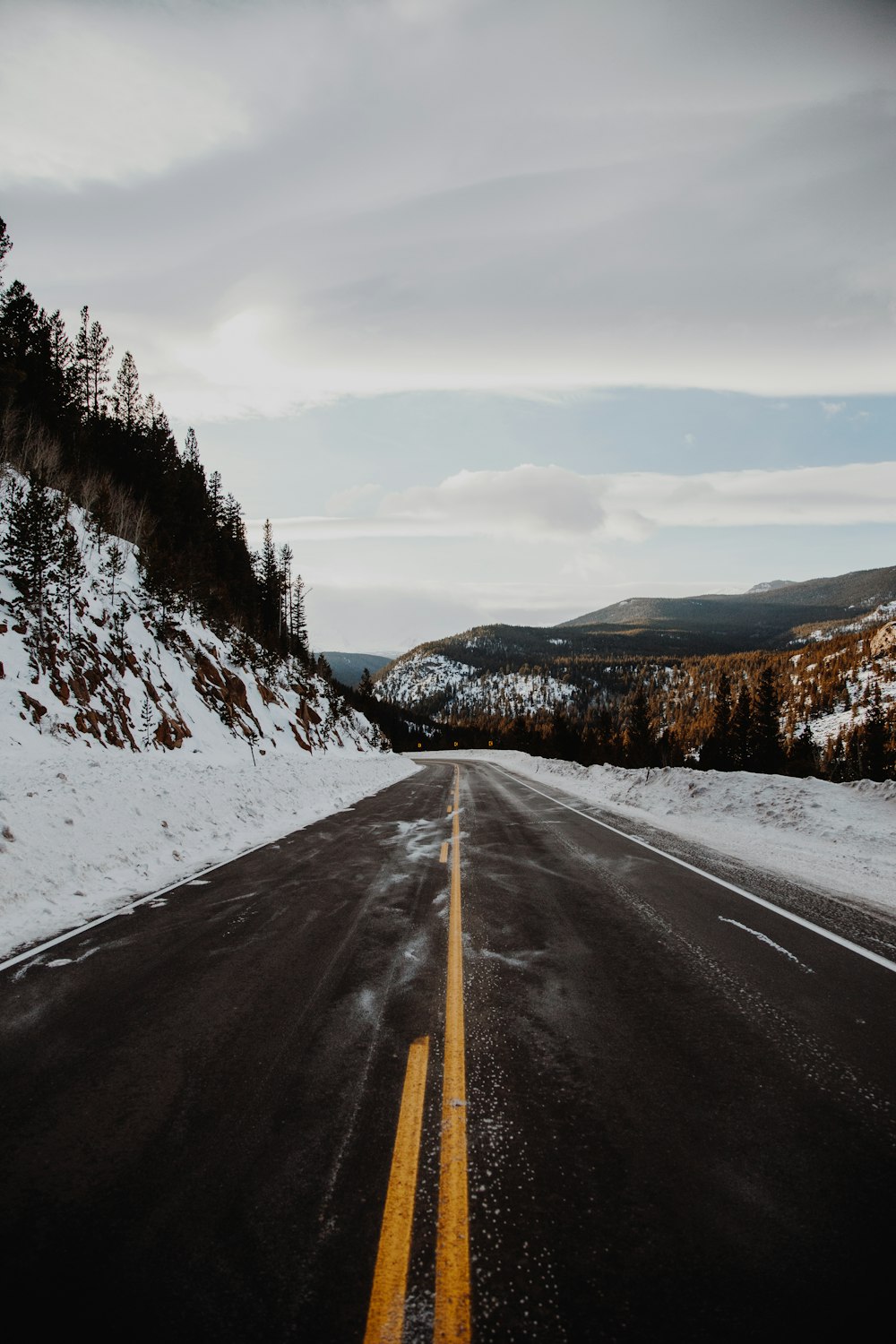 black asphalt road between snow covered ground during daytime