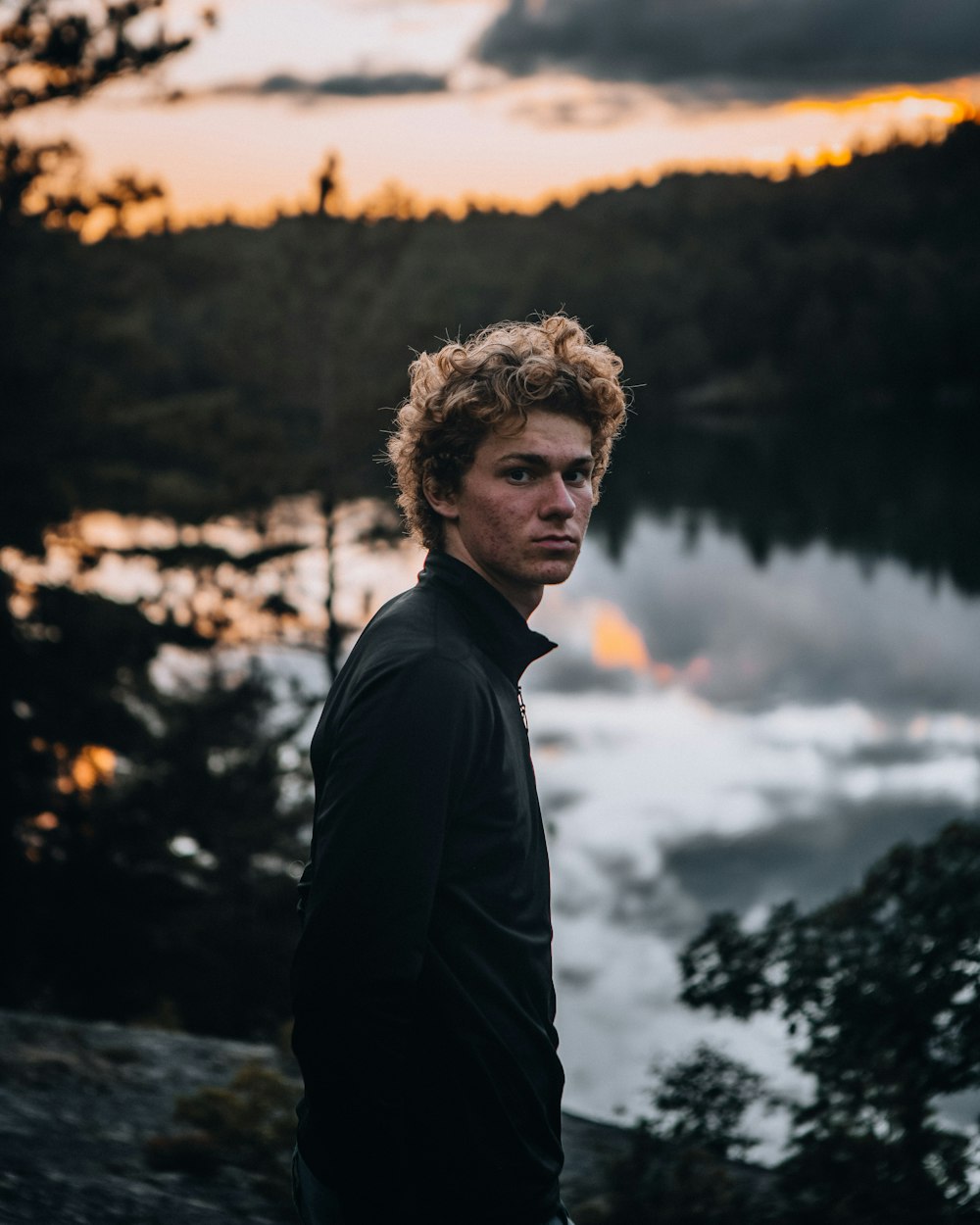 man in black jacket standing near lake during daytime