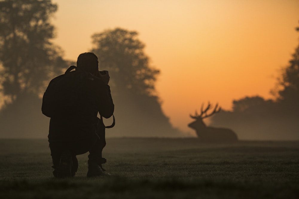 silhouette d’homme debout sur le champ d’herbe pendant le coucher du soleil