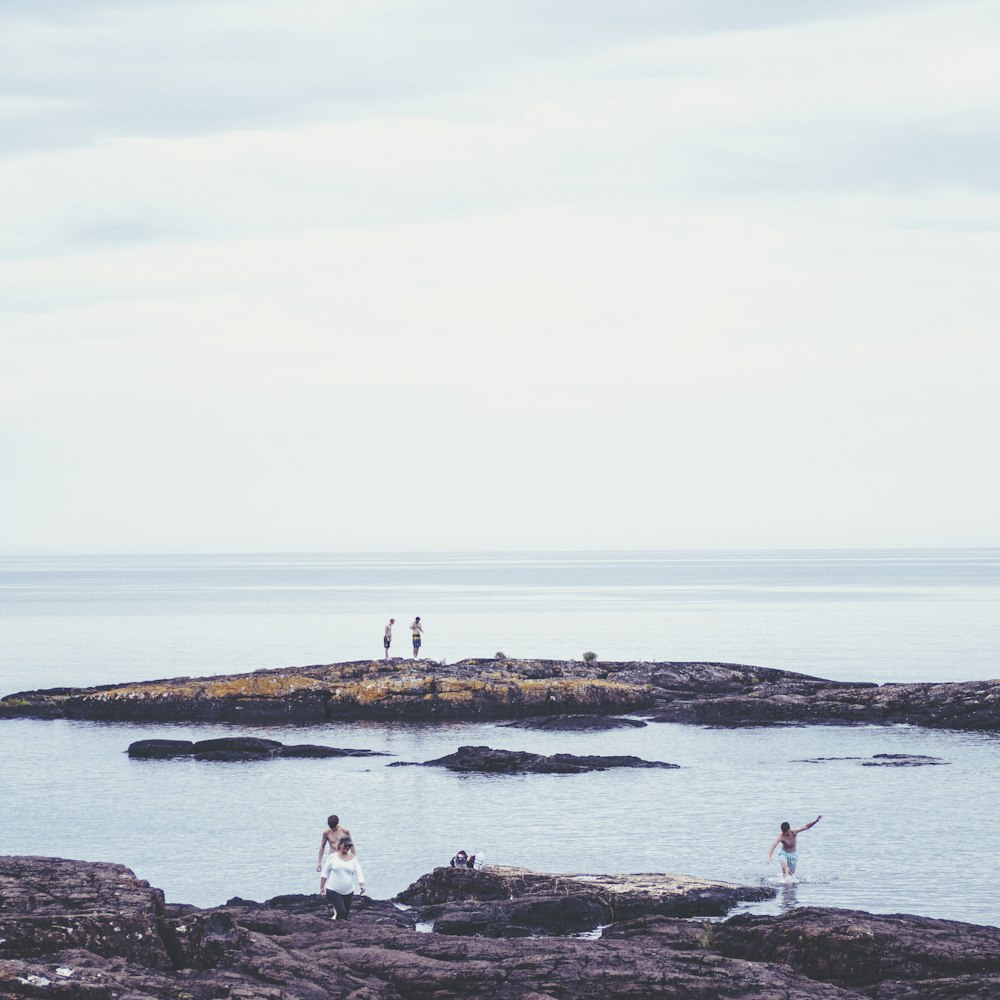 people standing on rock formation near sea during daytime