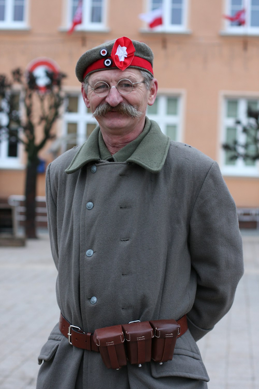 man in green coat wearing red cap standing on street during daytime