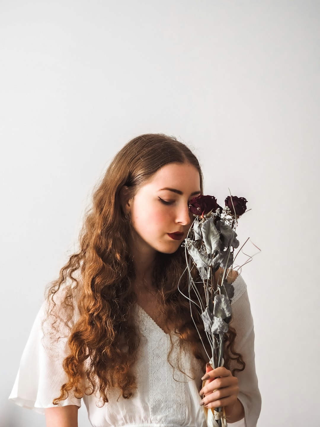 woman in white shirt holding flower