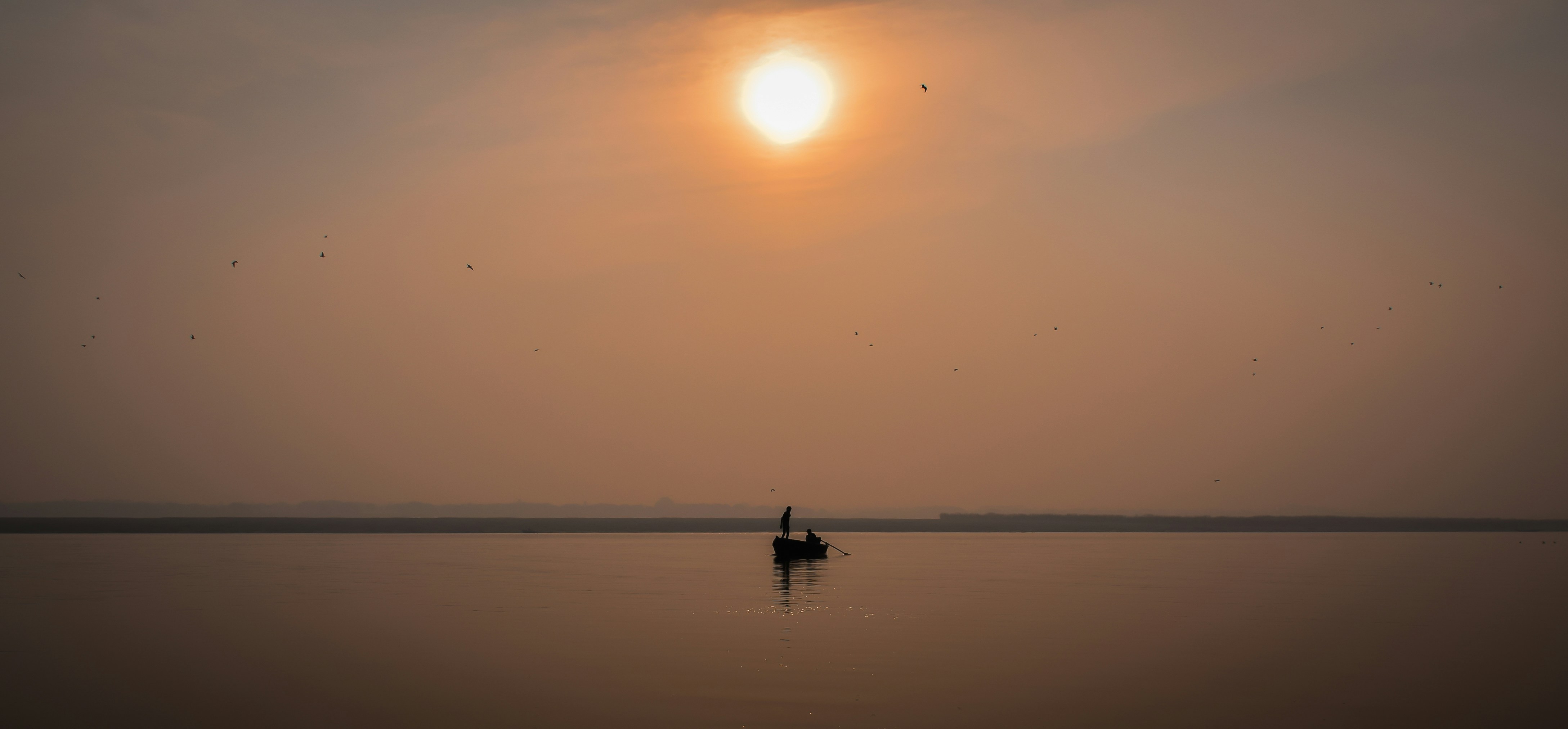 silhouette of person riding boat on sea during sunset