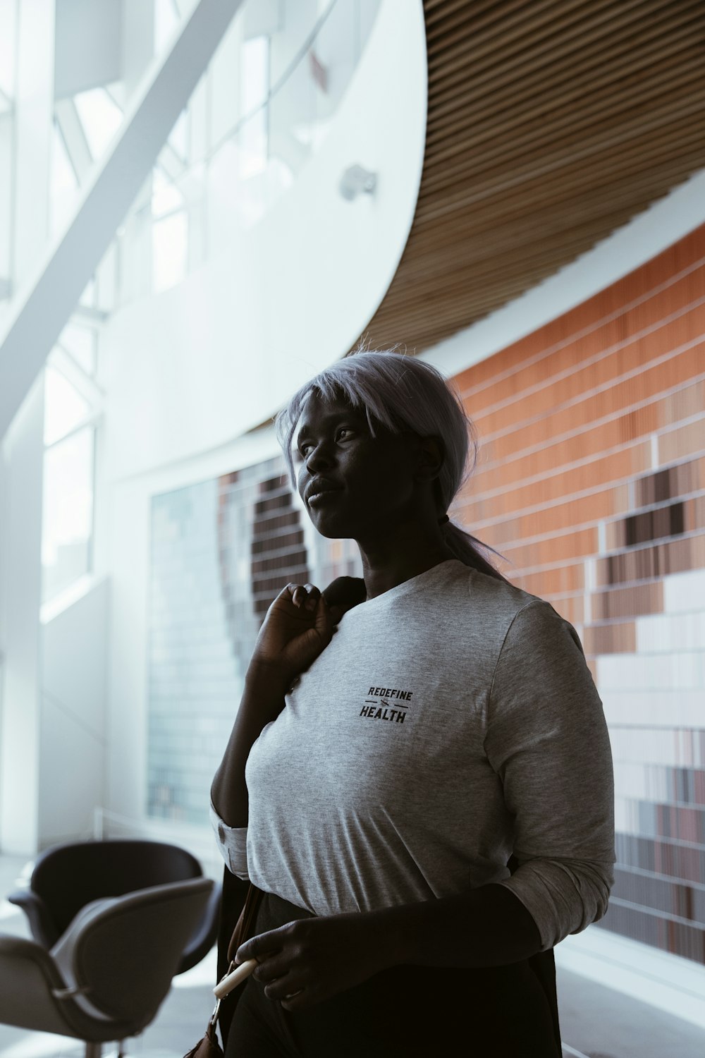 woman in gray crew neck long sleeve shirt standing near window during daytime