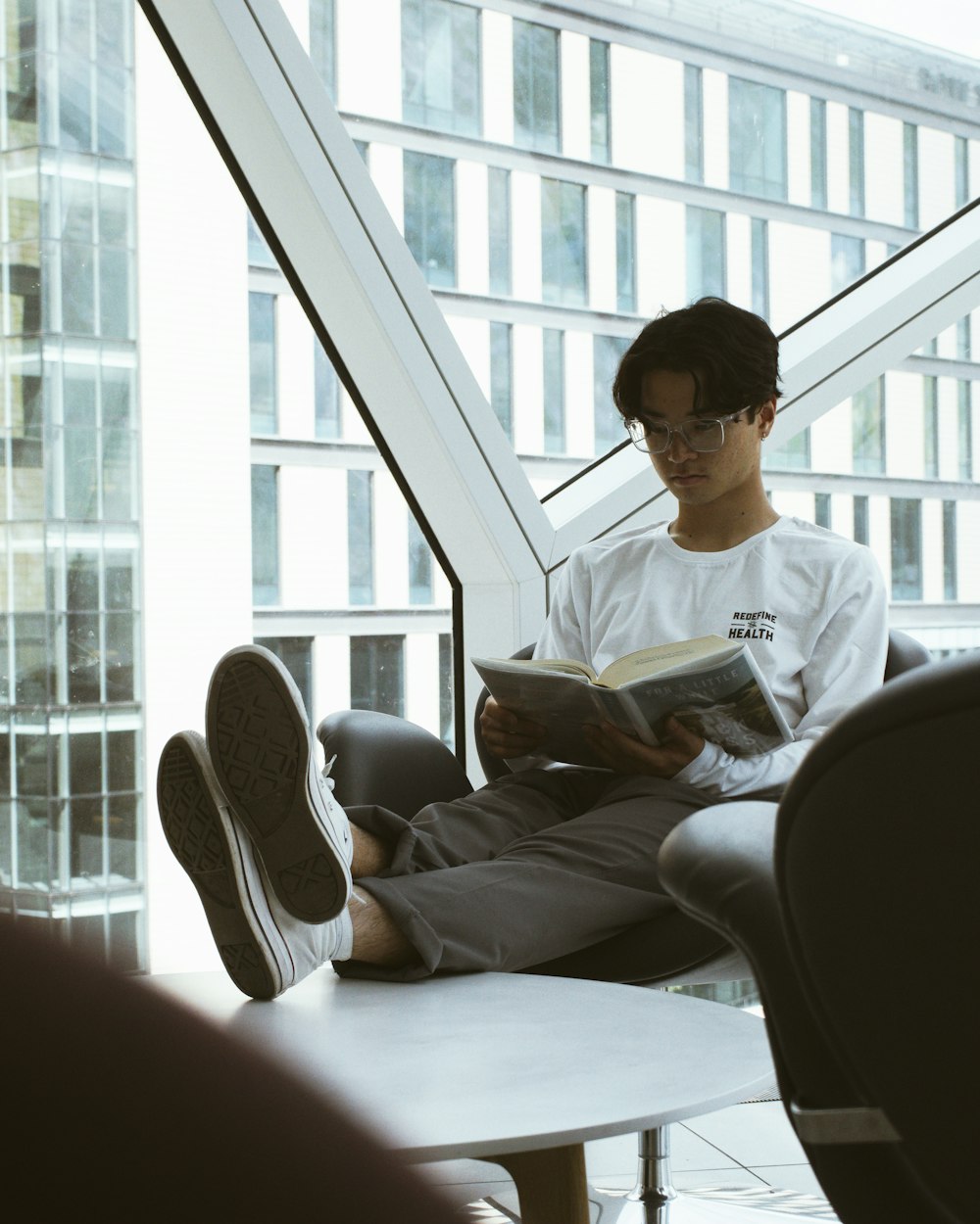 man in white crew neck t-shirt sitting on black leather chair