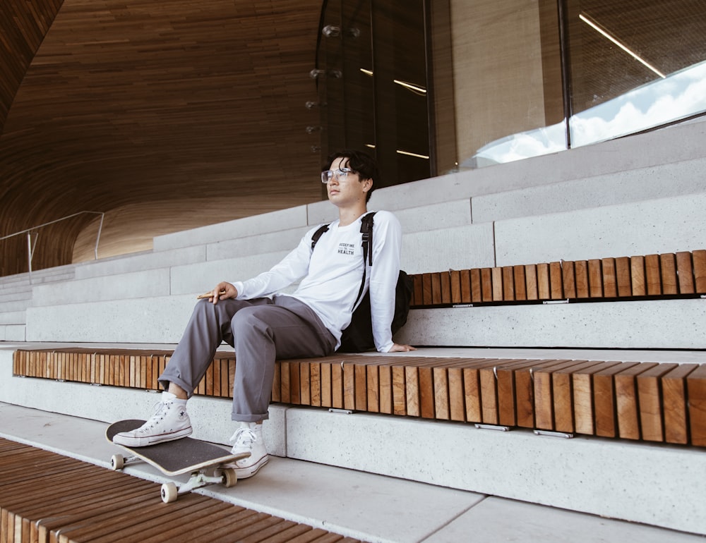 man in white dress shirt and gray pants sitting on brown wooden bench