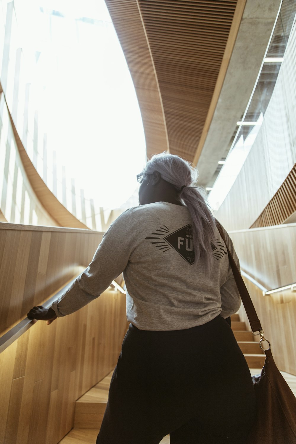 woman in gray long sleeve shirt and black skirt standing on brown wooden staircase