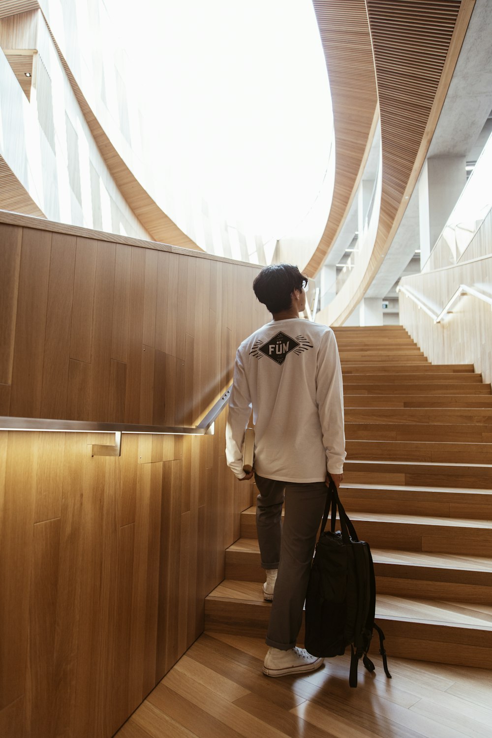 man in white dress shirt and black pants standing on brown wooden staircase