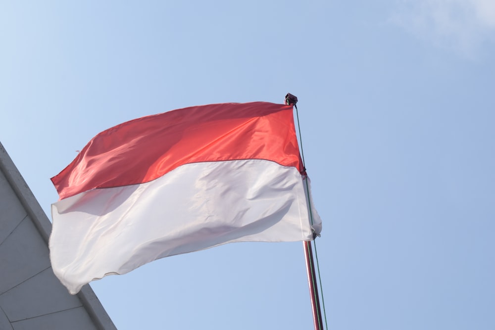bandeira branca e vermelha sob o céu azul durante o dia