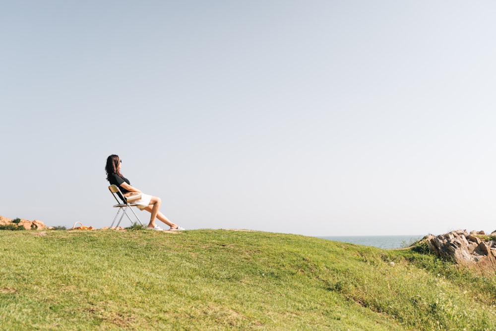 woman in black shirt sitting on chair on green grass field during daytime