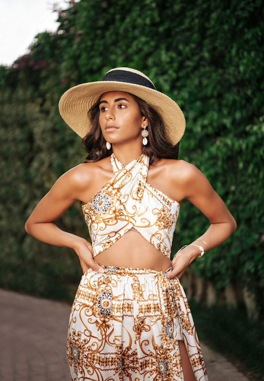 Mujer con vestido floral marrón y blanco con tirantes finos con sombrero marrón para el sol