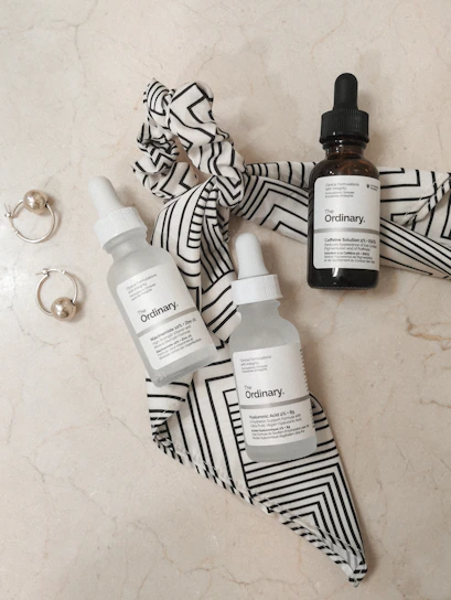 Elegant flat lay of luxurious skincare bottles with pink and gold accents on a black marble surface.