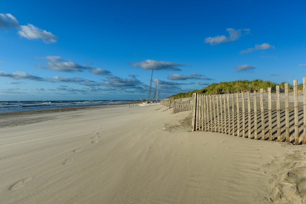 brown wooden fence on beach during daytime