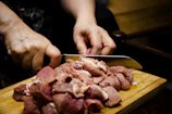 Butcher carefully slicing pork cuts on rustic wooden board