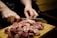 A butcher slicing fresh meat on a wooden cutting board.