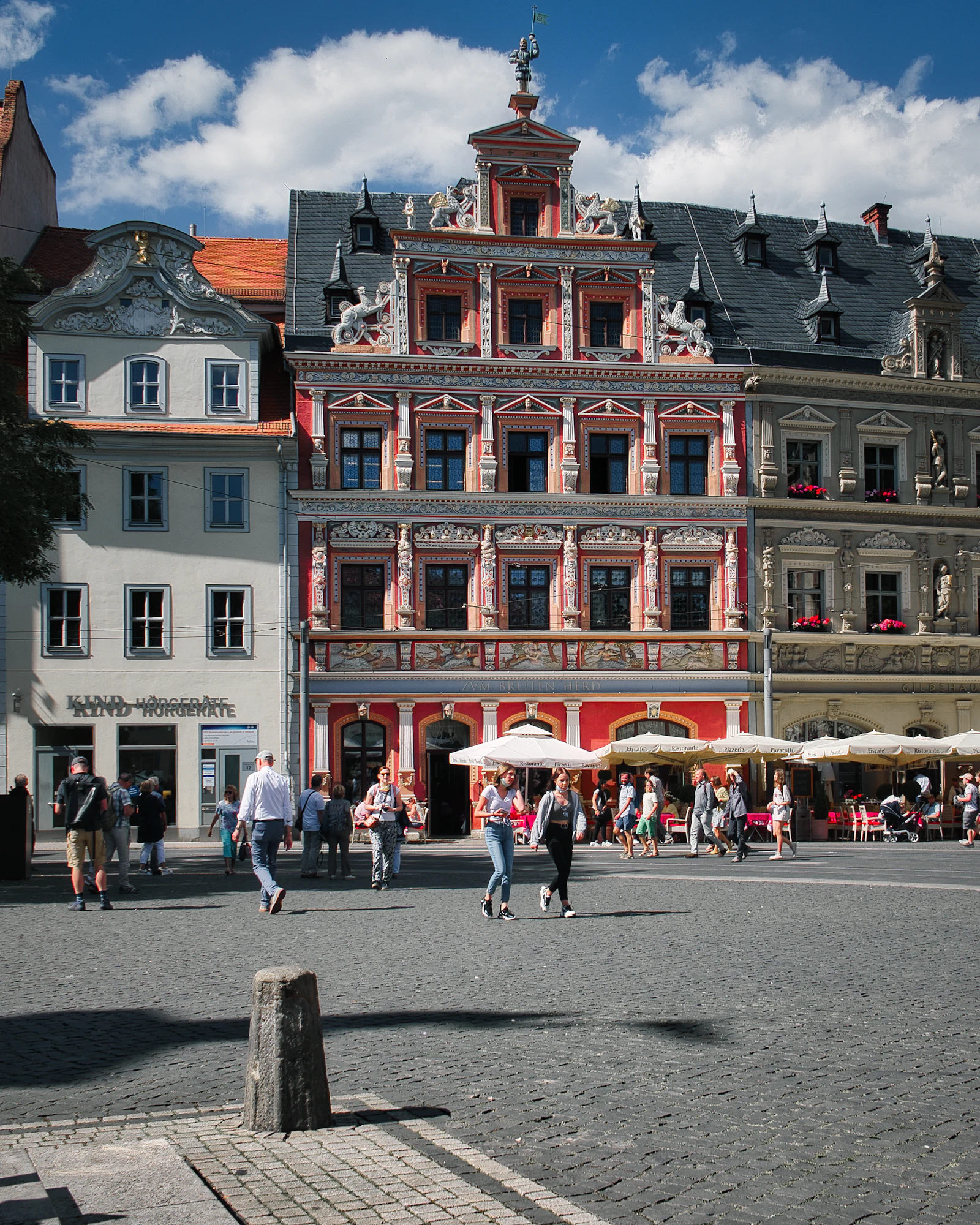 Menschen in einer Altstadtstraße mit rotem Gebäude