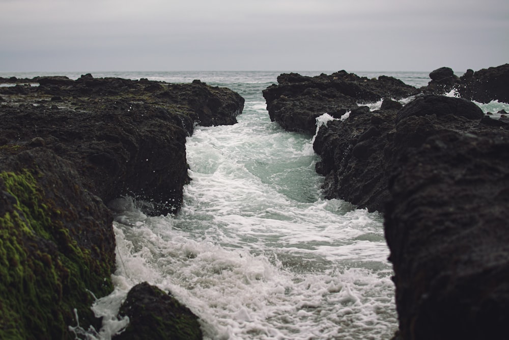 ocean waves crashing on black rock formation during daytime