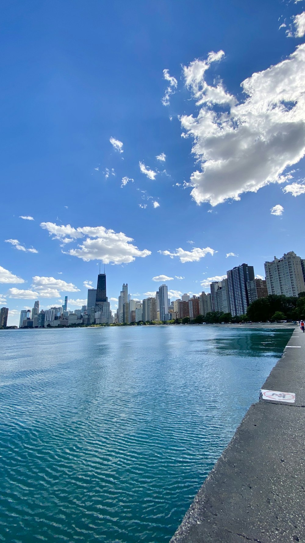 city skyline across body of water under blue and white sunny cloudy sky during daytime