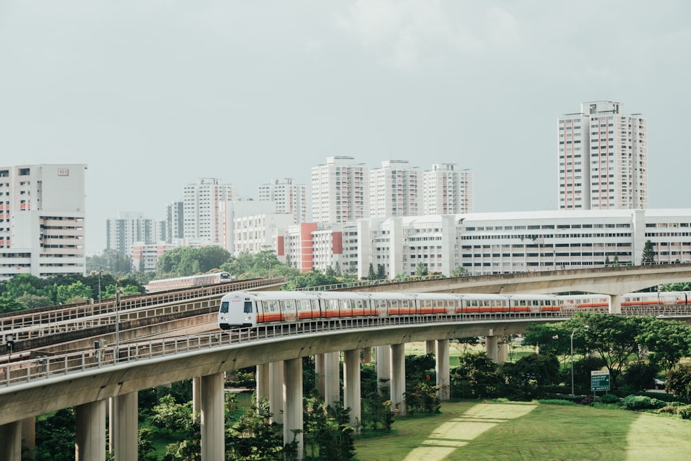 Tren rojo y blanco en el riel cerca de los edificios de la ciudad durante el día