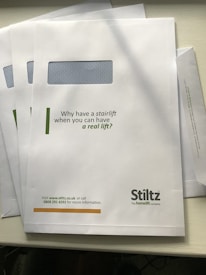 A white envelope is shown with a rectangular window and printed text. The text reads, 'Why have a stairlift when you can have a real lift?' At the bottom, contact information for a company named Stiltz is provided, including a website and phone number.