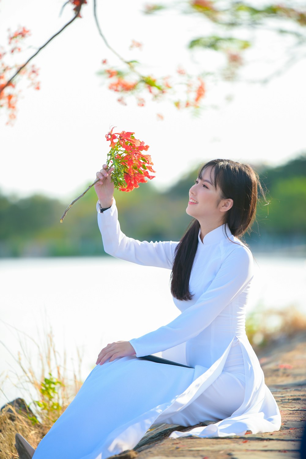 분홍색 꽃을 들고 흰색 긴 소매 드레스를 입은 여자