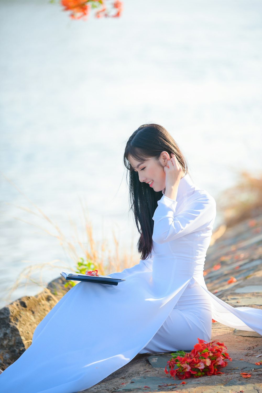 昼間、茶色の岩の上に座る白い長袖ドレスを着た女性