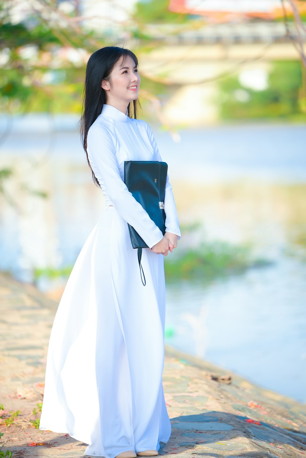 Frau in weißem langärmeligem Kleid mit schwarzem Buch