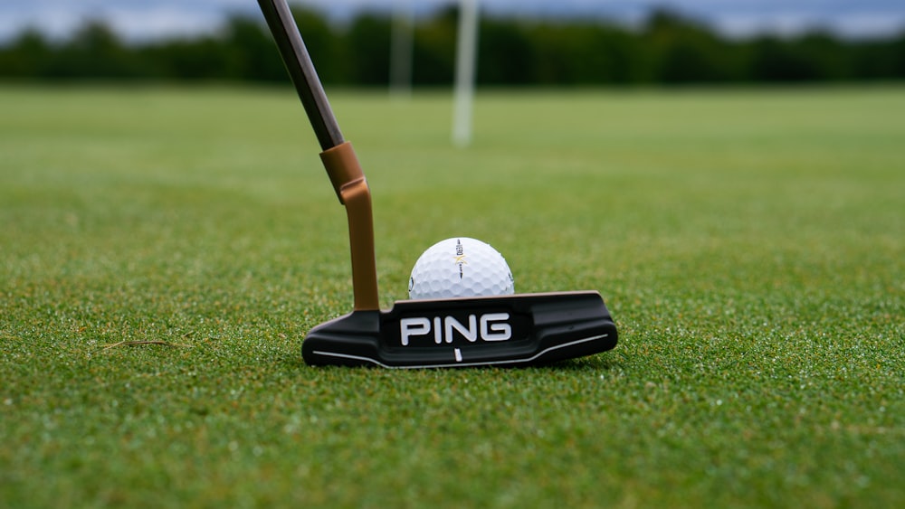 weißer Golfball auf schwarz-weißem Golfschläger