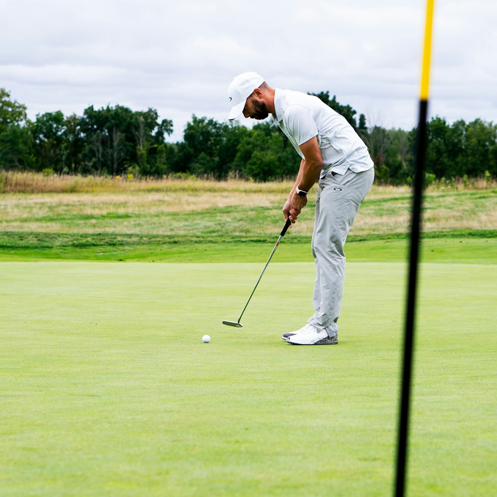 man in white shirt and white pants playing golf during daytime