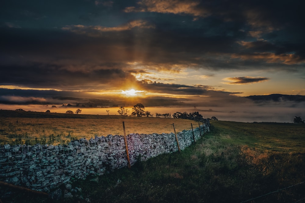 green grass field under cloudy sky during sunset