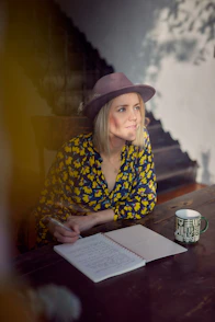 woman in blue and yellow floral long sleeve shirt wearing brown fedora hat