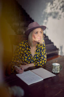 woman in blue and yellow floral long sleeve shirt wearing brown fedora hat