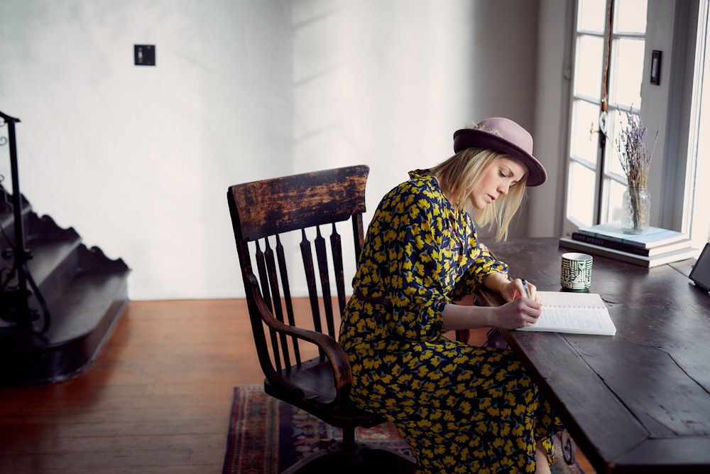 woman in yellow and black floral dress sitting on brown wooden chair