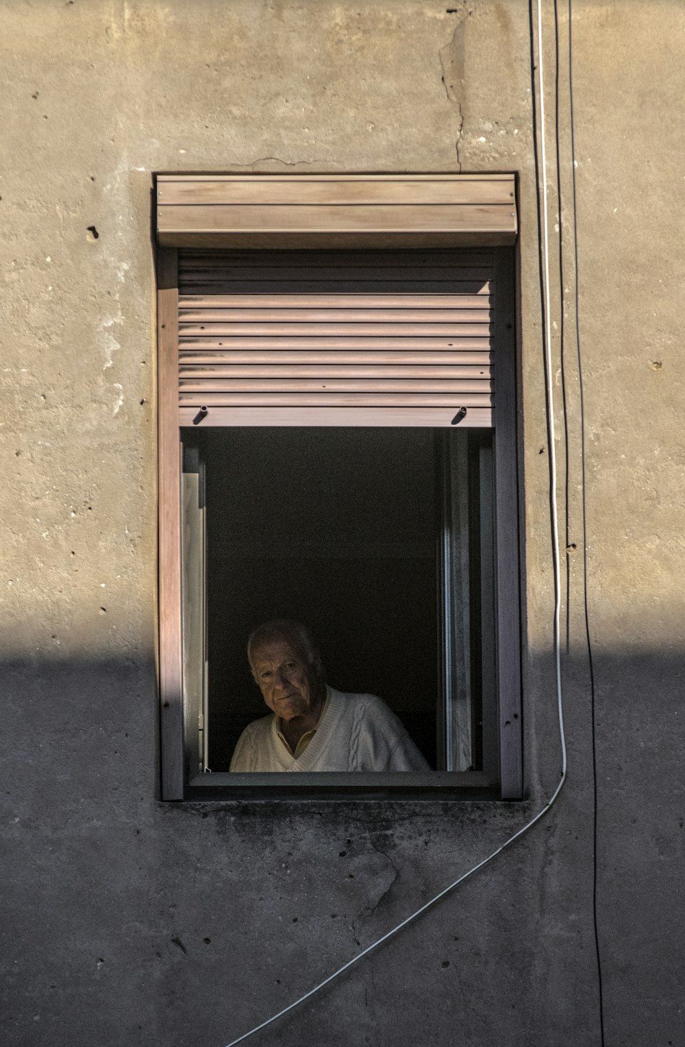 uomo in camicia bianca che si siede sulla finestra