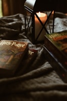 a candle sitting on top of a bed next to two books
